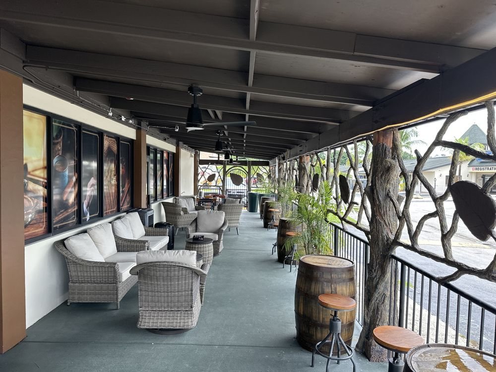The covered patio with wicker lounge chairs and barrel tables